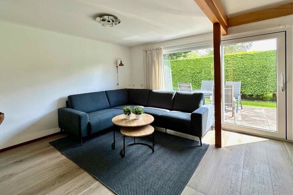 A modern living room with a sectional sofa, a round coffee table, and a large sliding glass door leading to an outdoor patio.
