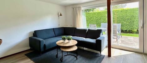 A modern living room with a sectional sofa, a round coffee table, and a large sliding glass door leading to an outdoor patio.