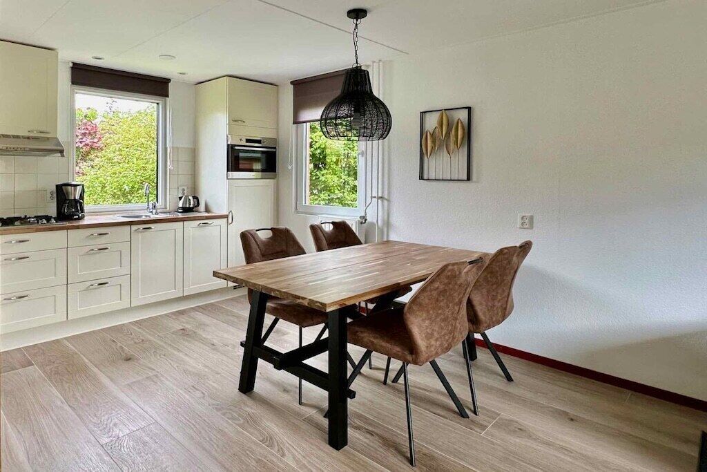 Una cocina moderna con armarios blancos, una mesa de comedor de madera y sillas marrones.