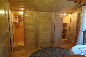 Een kamer met houten vloer, een bed, een vloerkleed en een garderobe met schuifdeuren.