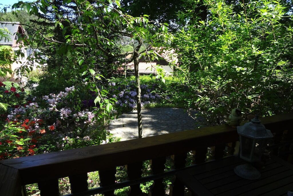 A garden with a stone pathway, a wooden deck, and a lantern.