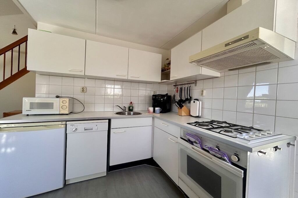 A compact kitchen with white cabinetry, a built-in microwave, a gas stove, and a dishwasher.