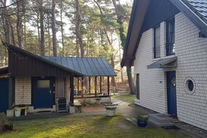 Asuinrakennus, jossa on katettu kuisti, tiilestä rakennettu päärakennus ja puinen varastorakennus.