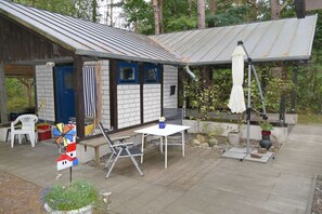 Un espacio al aire libre techado con una mesa, sillas, una decoración de molino y un paraguas blanco.