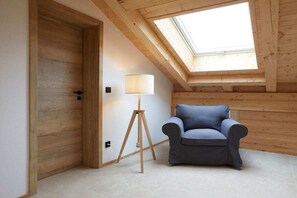 Ein Zimmer mit Oberlichter, einer Tür, einer Stehlampe und einem blauen Sessel.