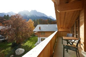 Ein Holzbalkon mit Tisch und Stühlen, mit Blick auf eine Berglandschaft.