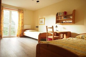 A room with a bed, a desk, and a chair, with a bookshelf and a window with curtains. - Holiday apartment with 2 bedrooms (Boltenhagen)