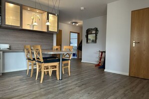 A modern kitchen with wooden cabinets, a dining table with chairs, and pendant lighting. - Holiday apartment with 2 bedrooms (Boltenhagen)