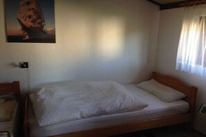Ein Einzelbett mit Holzrahmen und weißer Bettwäsche in einem Zimmer mit weißen Wänden.