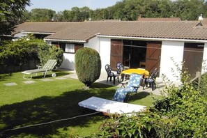 Ein Wohnhaus mit Terrasse, Rasenfläche und kleinem Garten.