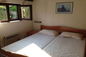 A bedroom with a bed, a window, a radiator, and a picture on the wall. - Dune House Holiday Park Duinendaele (De Panne-Adinkerke)