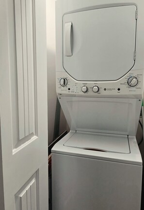 A front view of a white front-loading washing machine with control knobs and a door handle. - Peaceful Lakefront Retreat + Covered Dock + Fishing Pier + Firepit + Amenities (Ridgeway)
