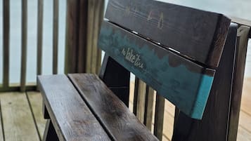 Un banc de fusta amb respatller damunt d'un pont de fusta, amb vista a un cos d'aigua.