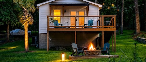 A two-story house with a balcony, a fire pit, and outdoor seating.