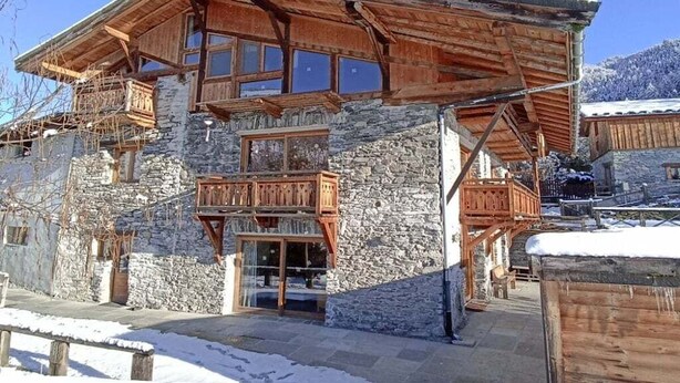 A multi-story stone building with wooden balconies and large windows.
