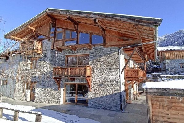 A multi-story stone building with wooden balconies and large windows.