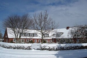 Een klassiek gebouw met een sneeuwbedekte kap en een bordje dat aangeeft dat het een pension is.