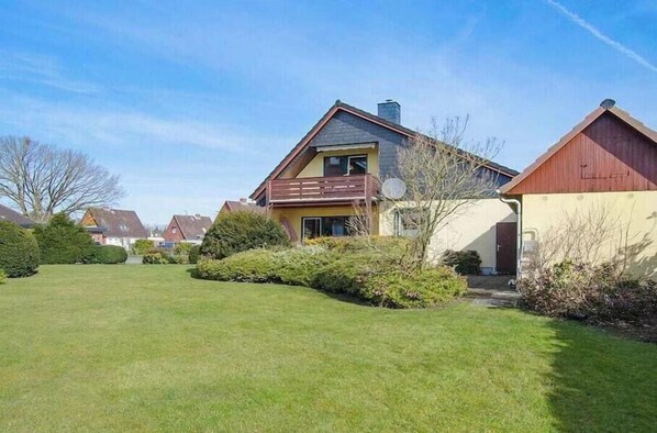 Een woonhuis met een schuin dak, een balkon en een verzorgd gazon.