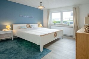 Een slaapkamer met een bed, nachtkastjes, een raam met gordijnen en uitzicht.