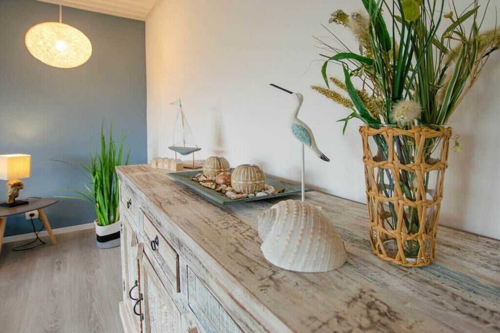 A rustic wooden dresser with decorative shells and a woven basket with greenery.