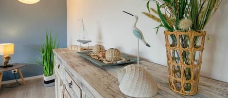 A rustic wooden dresser with decorative shells and a woven basket with greenery.