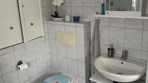 Ett litet badrum med toalett, handfat och spegel.