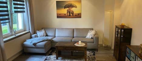 A living room with a sofa, a coffee table, a painting, and a cabinet.