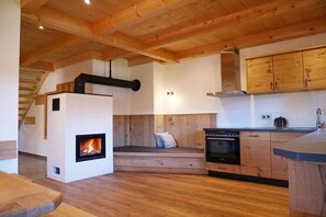 A modern kitchen with wooden beams, a built-in fireplace, and wooden cabinetry. - Holiday apartment with 3 bedrooms (Lenggries)