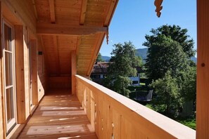 A wooden balcony with a view of a residential area and mountains. - Holiday apartment with 3 bedrooms (Lenggries)