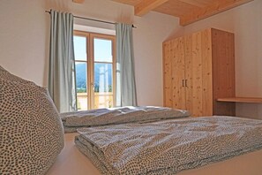 A bedroom with two beds, a window with curtains, and a wooden wardrobe. - Holiday apartment with 3 bedrooms (Lenggries)