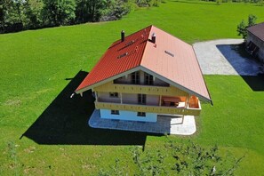 Una casa de dues plantes amb teulada vermella, un balcó al pis superior i fonaments de pedra.