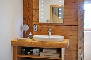 Un bagno con un mobile bagno in legno, uno specchio rotondo, un lavandino e un porta asciugamani.