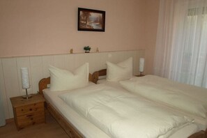 A bedroom with a double bed, wooden headboard, bedside tables, and a small decorative item on the wall.