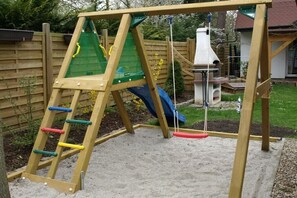 Une structure de jeu en bois, dotée d’un toboggan et d’éléments d’escalade.