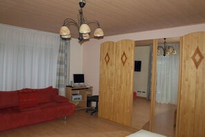 A room with a red sofa, a desk with a computer, and a wooden partition.