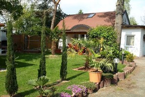 A residential property with a well-maintained lawn, a variety of potted plants, and a wooden fence. - Holiday apartment with 1 bedroom (Markkleeberg)
