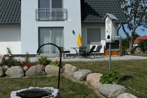 Una casa moderna amb un patí, mobiliari exterior i un allotjament per ocells.