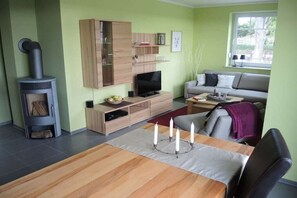 Ein Wohnzimmer mit Fernseher, Sofa und Kamin.