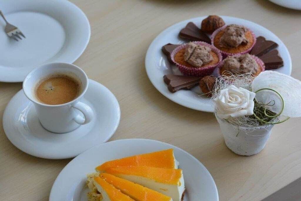 Une table à manger avec des assiettes de nourriture, une tasse de café et une petite plante en pot.