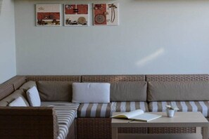 A corner room with a brown sofa, a striped cushion, a small table with a book and a plant, and three wall art pieces. - Holiday apartment with 1 bedroom (Lubmin)