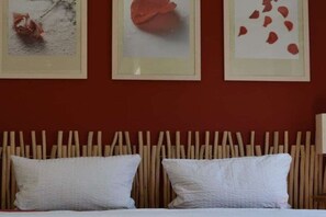 A bed with white pillows and a wooden headboard, framed by three artworks on the wall. - Holiday apartment with 1 bedroom (Lubmin)