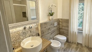 Une salle de bain moderne avec un grand miroir, deux lavabos, des toilettes et une orchidée en pot.