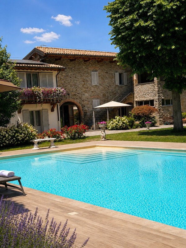 A stone building with a swimming pool, surrounded by greenery and flowers. - Vrbo Property (Arezzo)