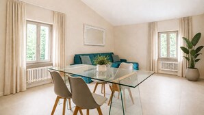 Un salon moderne avec une table à manger en verre, un canapé de couleur turquoise et une plante en pot.