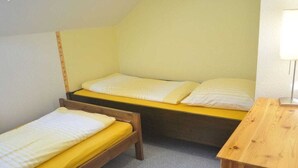Ein kleines, kompaktes Zimmer mit zwei Einzelbetten und einem Nachttisch aus Holz.