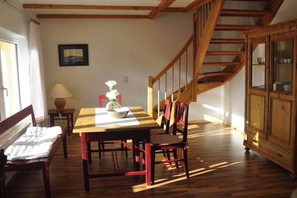 A dining area with a wooden table and chairs, a staircase, and a cabinet.