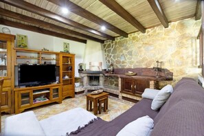 Ein Wohnzimmer mit Steinwand, Holzmöbeln, Kamin und Fernseher.