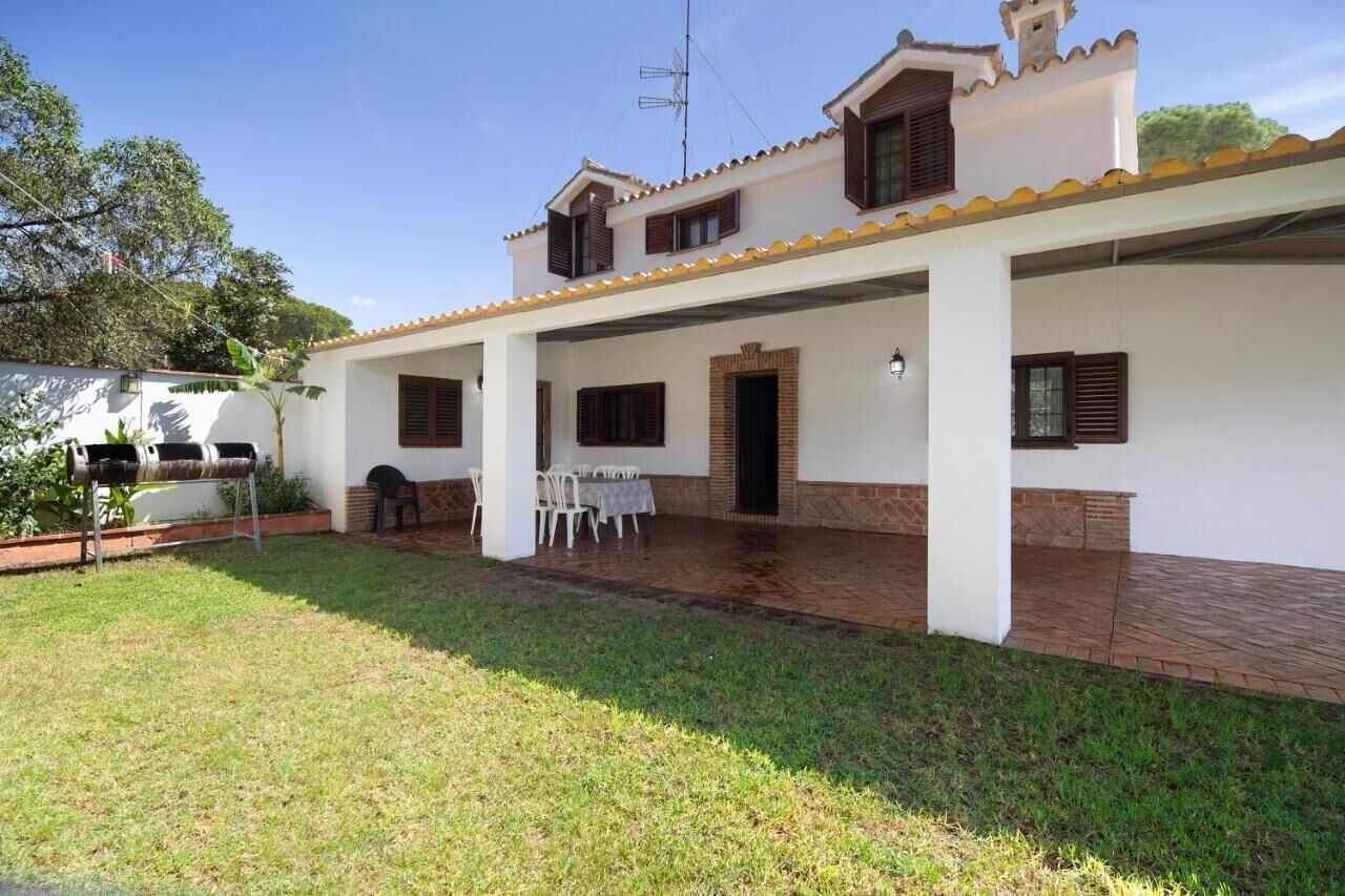 A two-story house with a covered patio, a barbecue grill, and a table set for dining.
