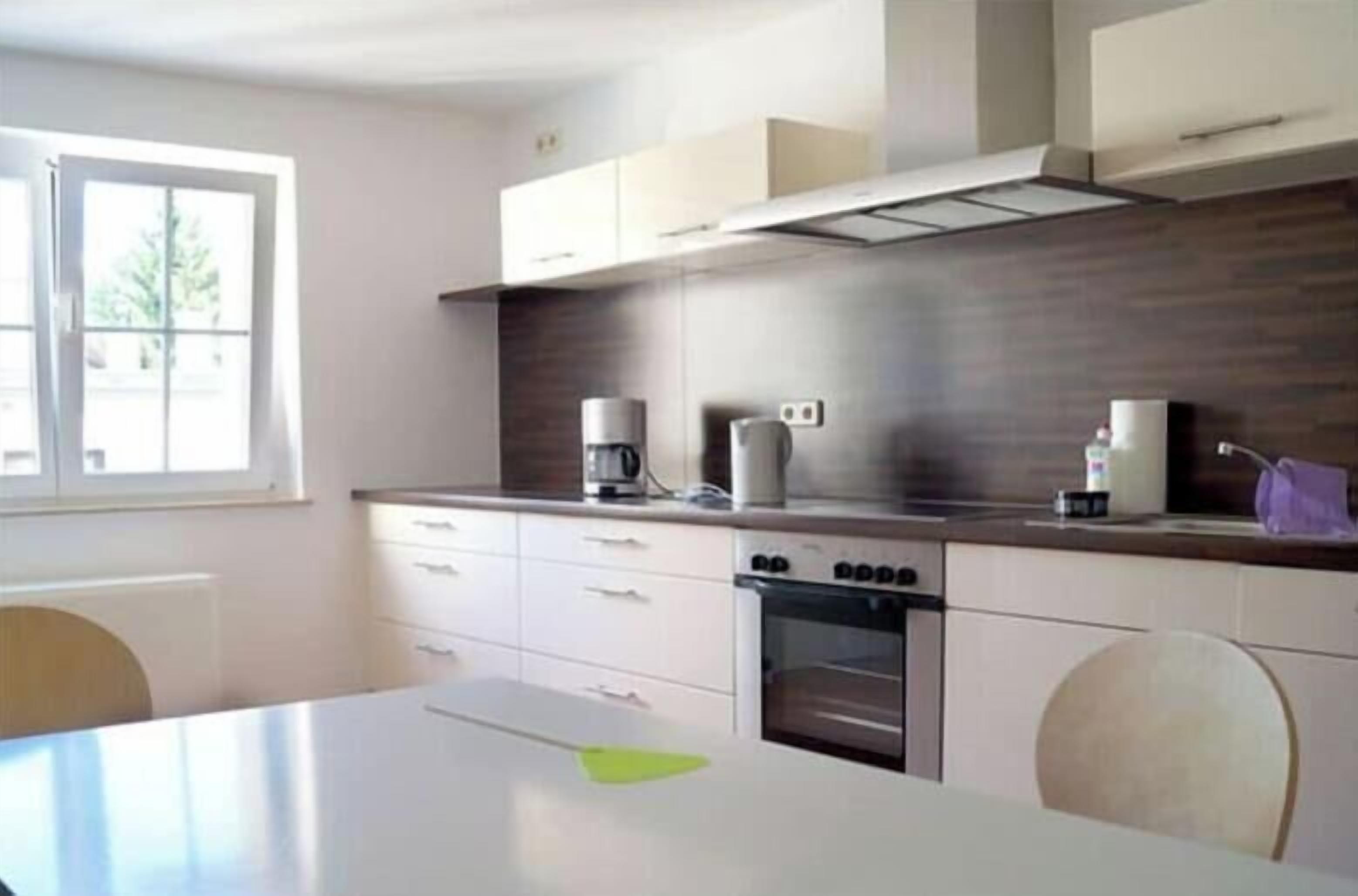 Una cocina moderna con horno empotrado, cafetera y ventana que proporciona luz natural.