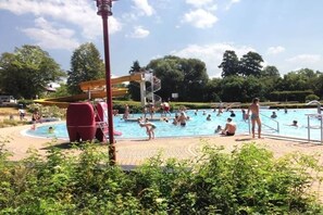 Ein Schwimmbeckenbereich mit Wasserrutsche und Rettungsturm.